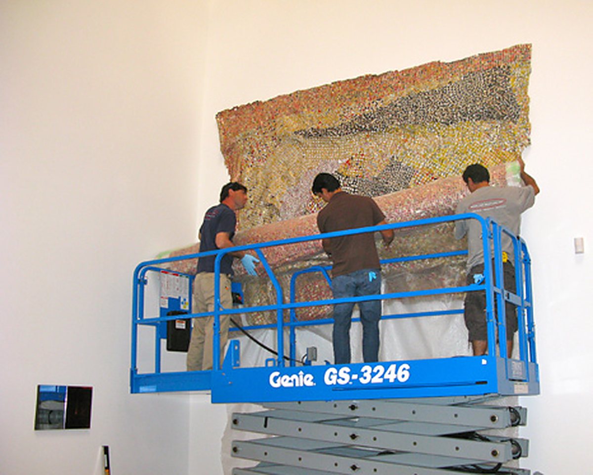 Miami Art Services technicians installing a large artwork from a lift